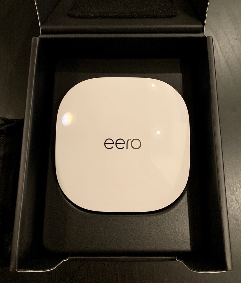 A poorly lit glamour shot of a single eero